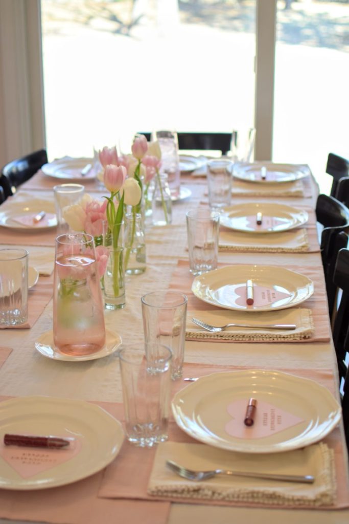 Pink Galentines Brunch Table setting with pink place mats and pink and white tulips